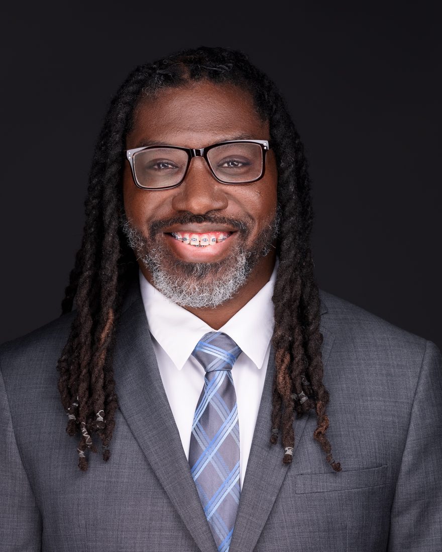 Lawrence Gray, smiling, in a gray suit and blue tie